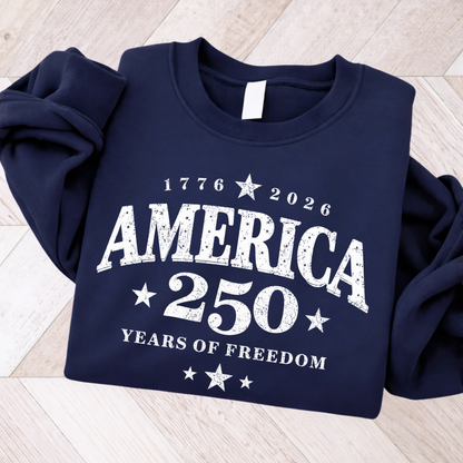 Navy blue sweatshirt with 'America 250 Years of Freedom' text on a light wooden floor.