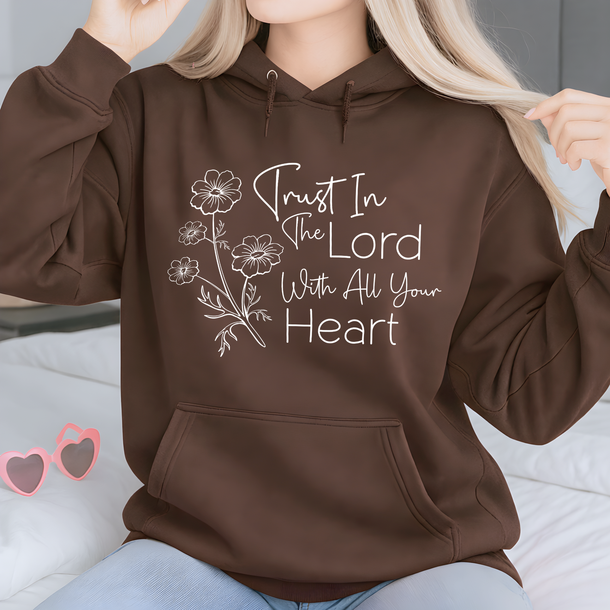 Brown hoodie with 'Trust In The Lord With All Your Heart' text and floral design, worn by a person.