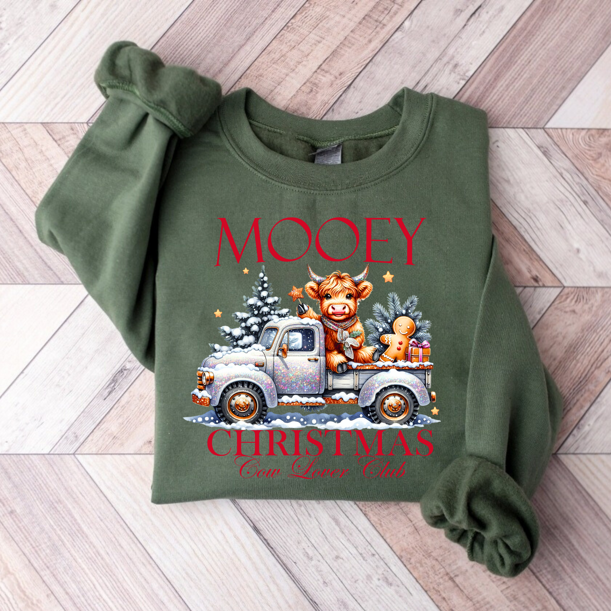 Green folded sweatshirt featuring festive cow in glitter truck
