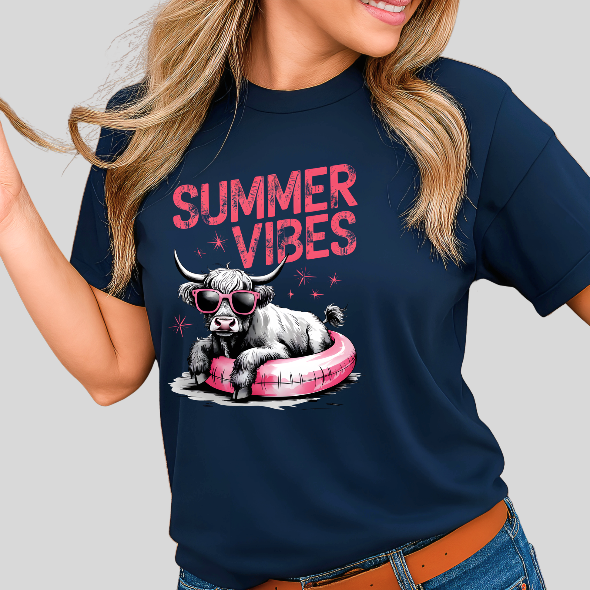 Person wearing a navy blue t-shirt with a graphic of a cow on a pink floatie and 'Summer Vibes' text.