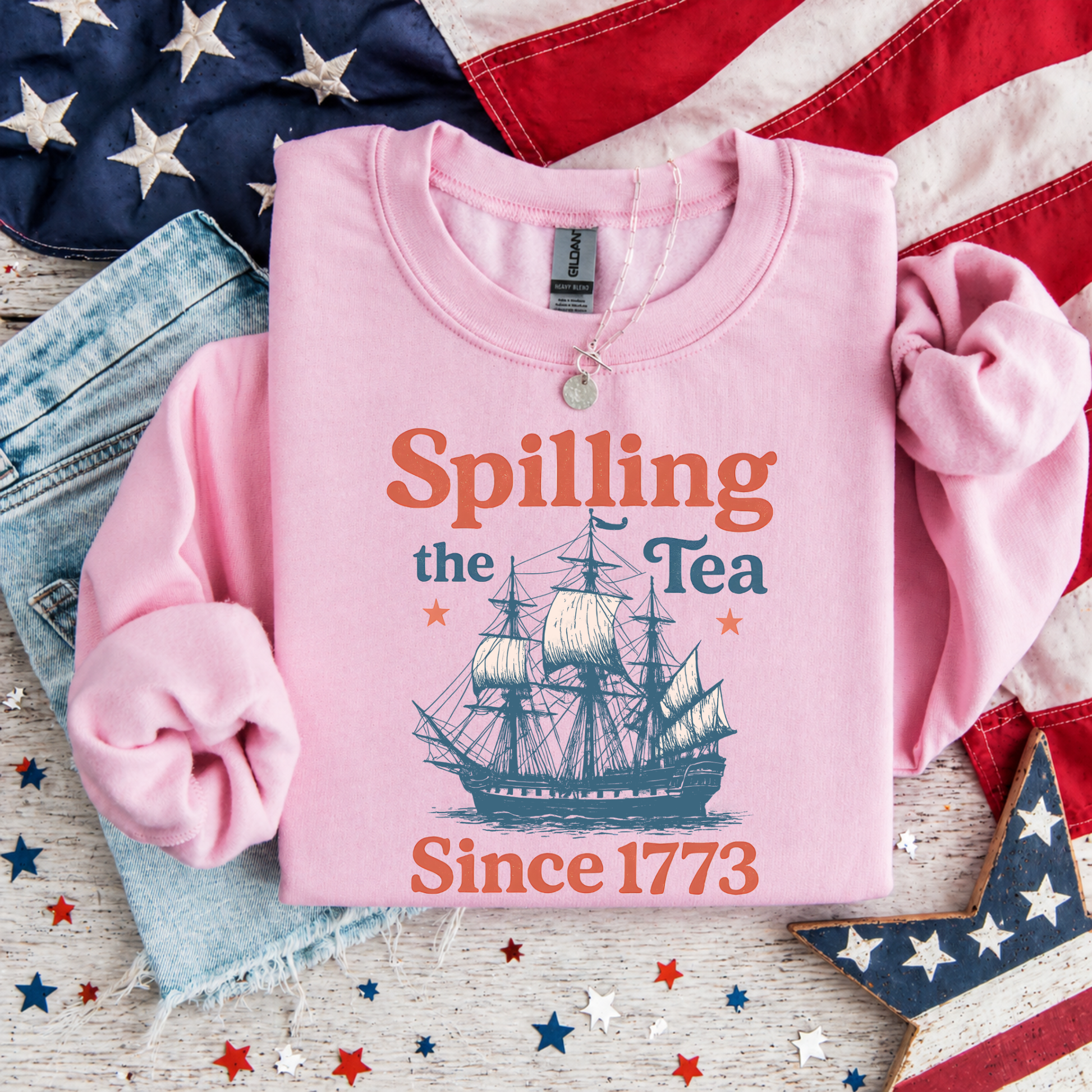Pink sweatshirt with ship graphic and text 'Spilling the Tea Since 1773' on an American flag background