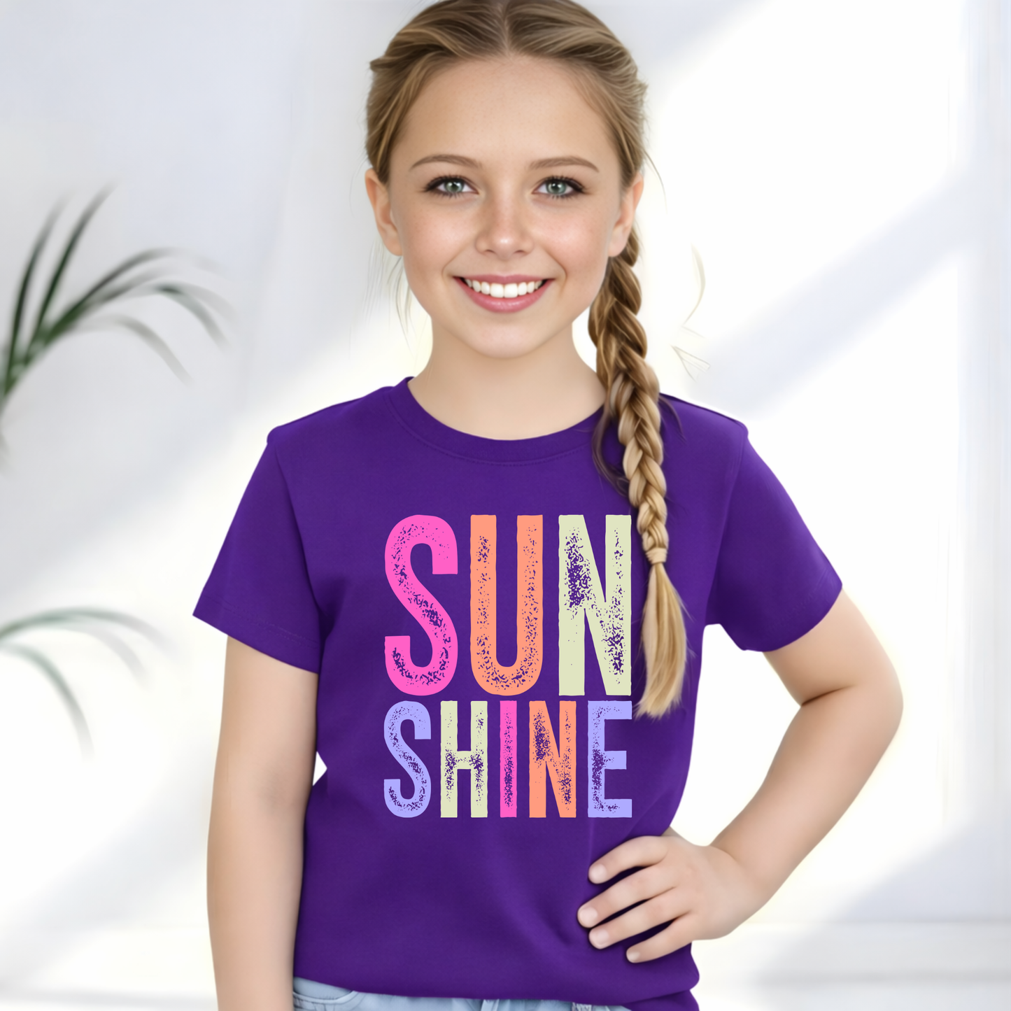 Young girl wearing a purple t-shirt with 'SUNSHINE' in colorful letters on a white background