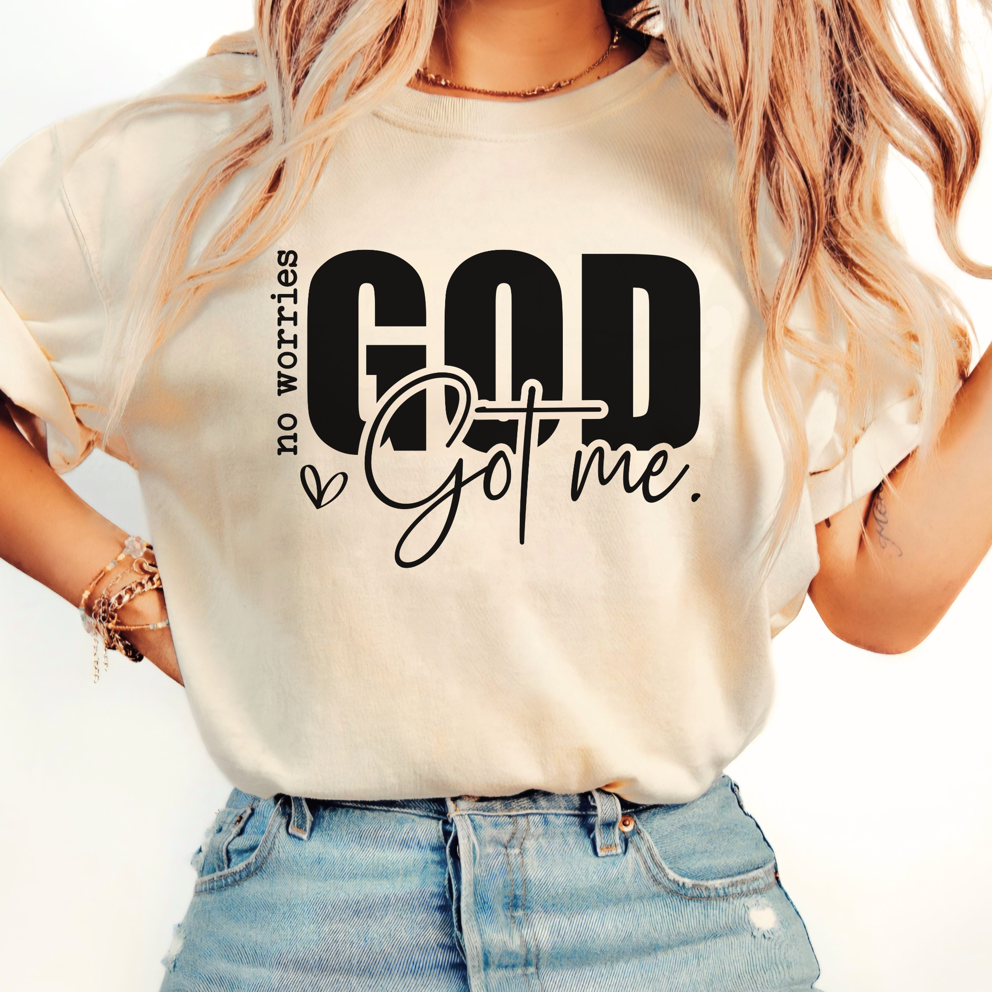 Woman wearing a sand colored Christan shirt with text "No Worries GOD Got me"