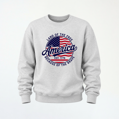 Sports gray crewneck sweatshirt flat lay with a red, white, and blue circular America graphic reading Land of the Free, Est. 1776, and Because of the Brave.