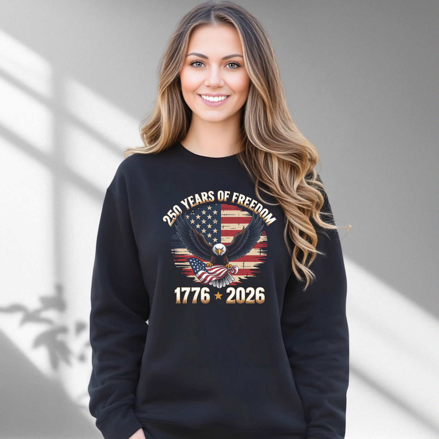 Woman wearing a black sweatshirt with an American flag and eagle design, standing against a gray background.