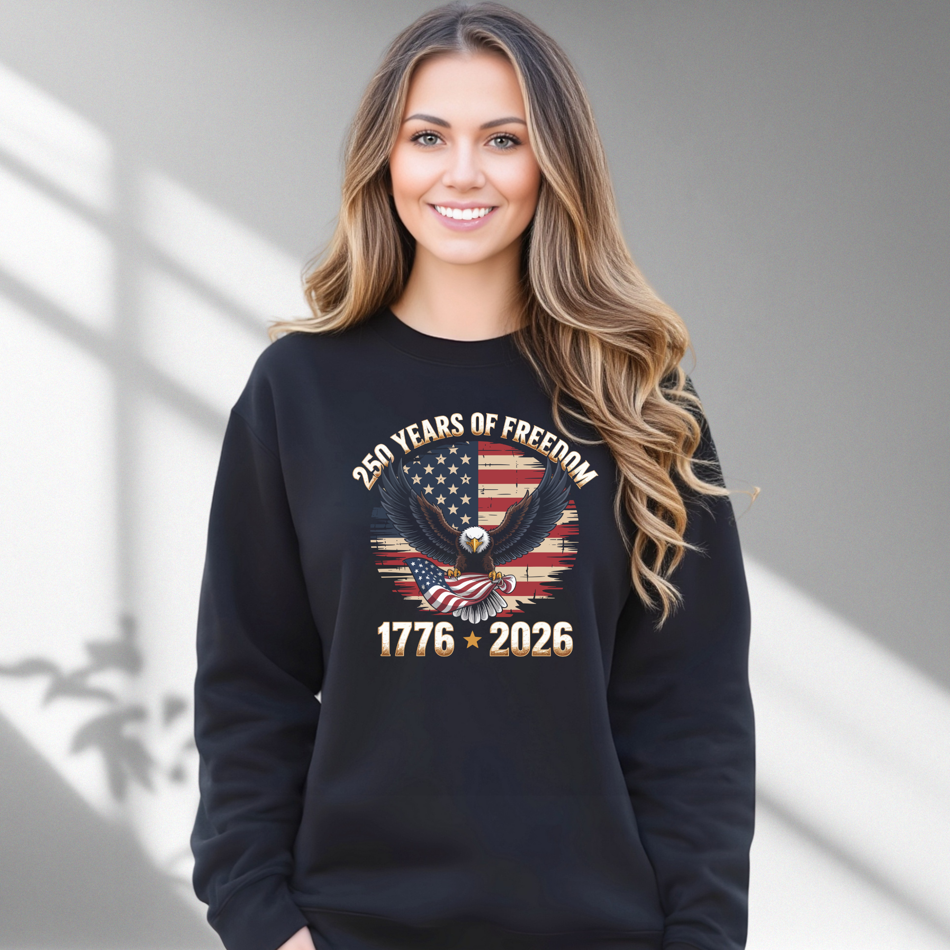 Woman wearing a black sweatshirt with an American flag and eagle design, standing against a gray background.