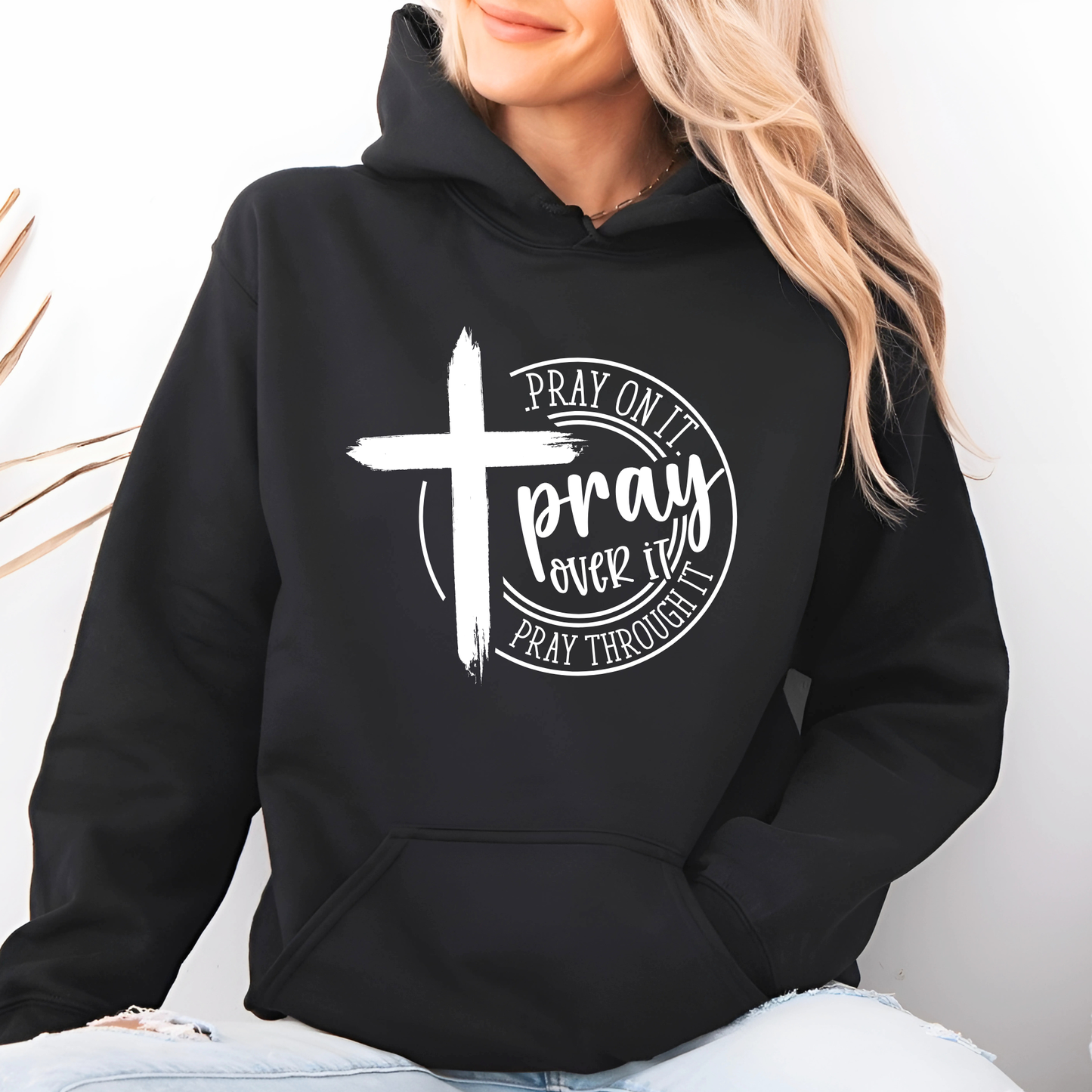 Woman wearing black Pray Over It Christian hoodie with cross design, front view