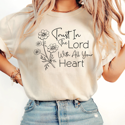 Person wearing a white t-shirt with 'Trust In The Lord With All Your Heart' text and floral design.