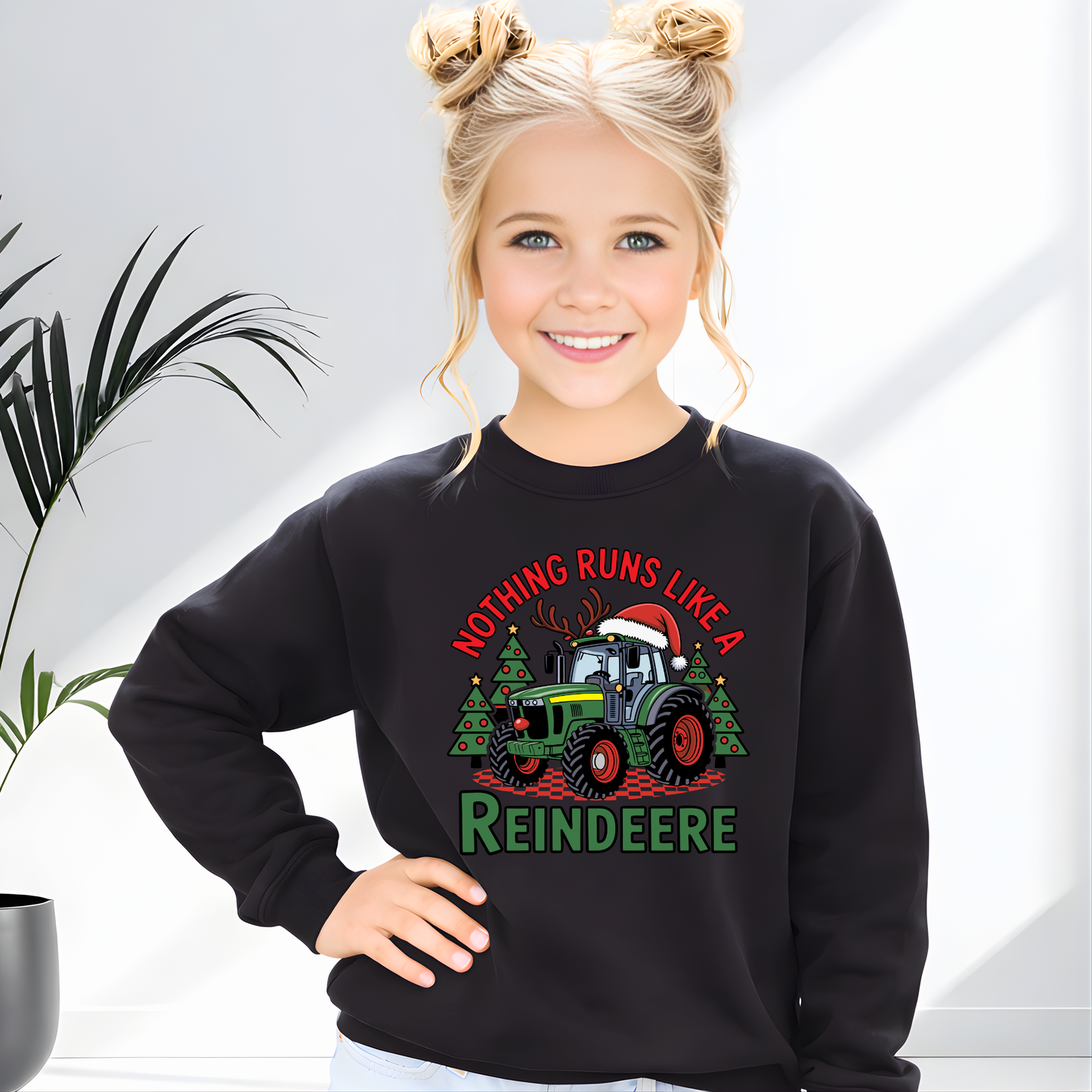 Child wearing a black sweatshirt with a Christmas-themed design, standing against a light background.