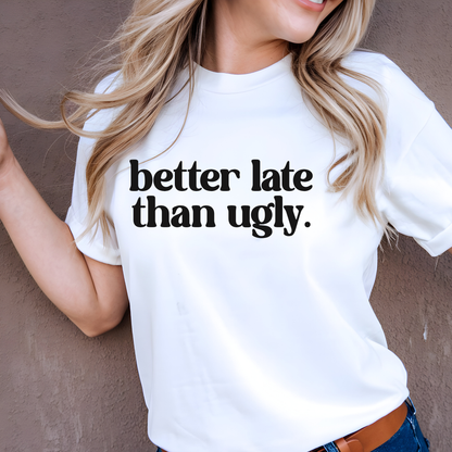 Girl wearing a white t-shirt with 'better late than ugly' text against a plain background