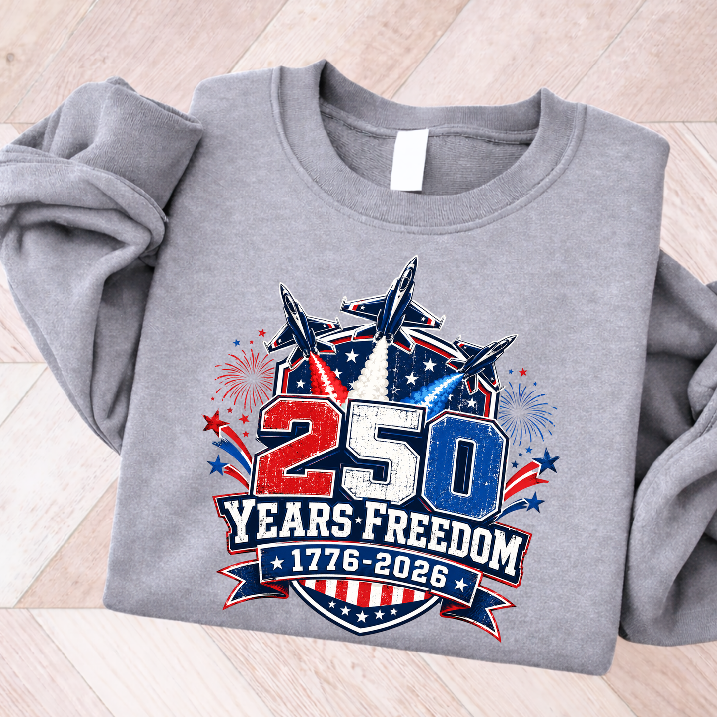 Gray sweatshirt with '250 Years Freedom 1776-2026' design on a wooden surface