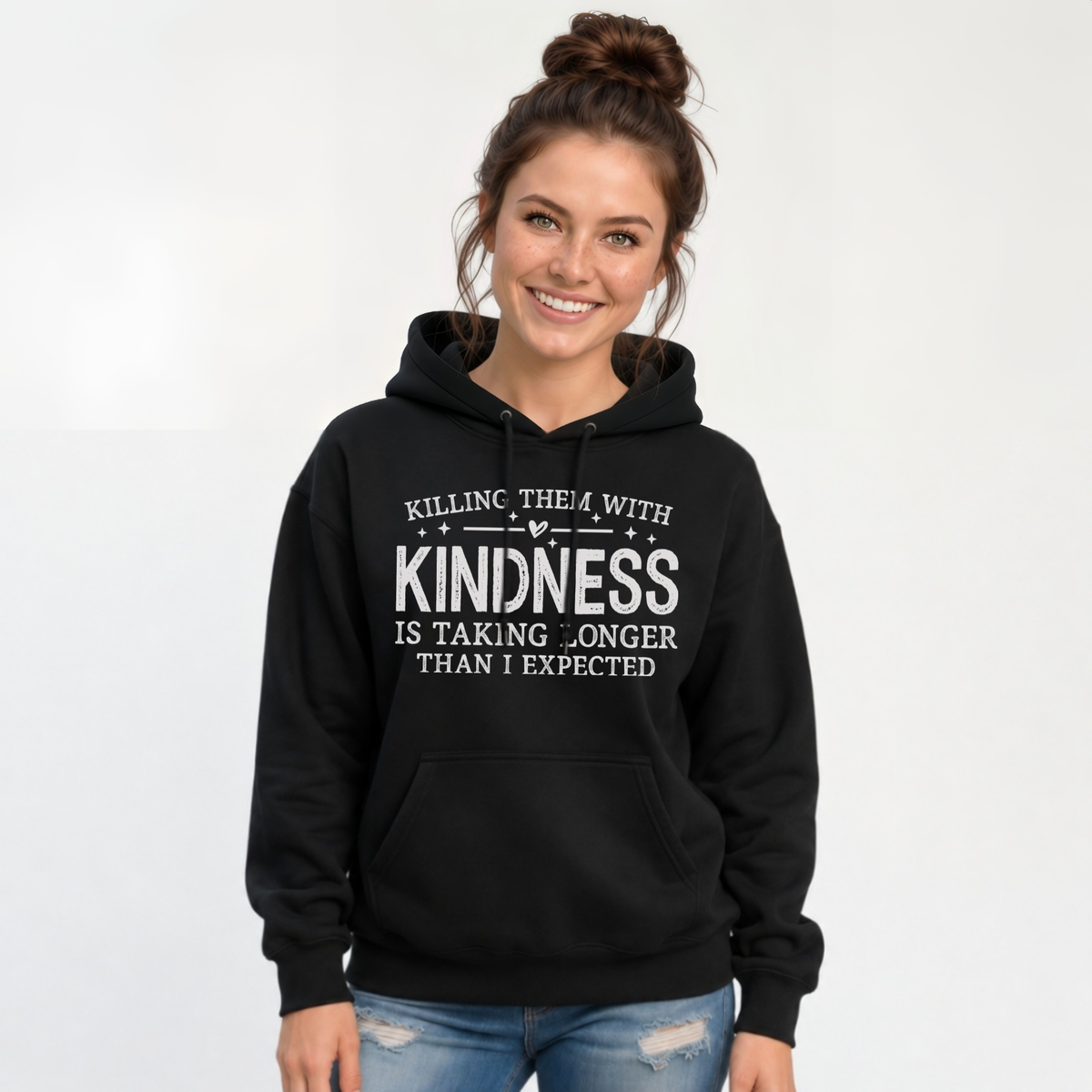 Woman wearing a black hoodie with white Killing Them With Kindness lettering against a white background.