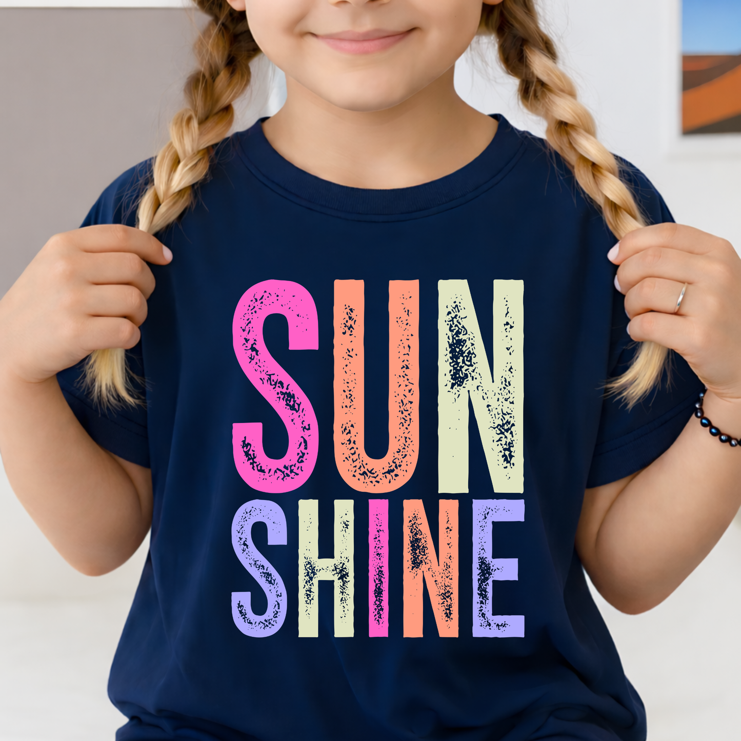 Child wearing a navy blue t-shirt with 'SUNSHINE' in colorful letters.