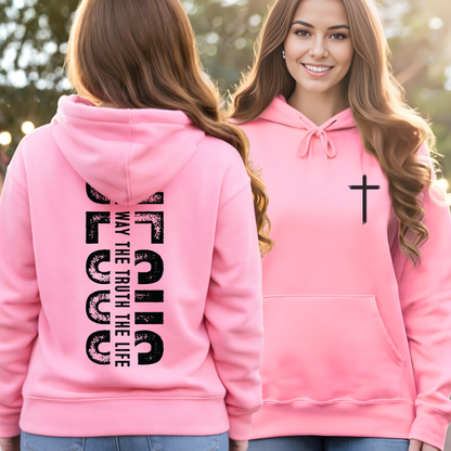 Pink hoodie with text and cross design worn by a person outdoors.