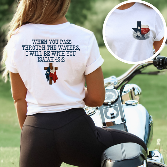 Outdoor lifestyle image of a woman wearing a white Christian T-shirt with “Pray for Texas” on the front and Isaiah 43:2 scripture with Texas flag and cross on the back. Perfect for faith-based Texas flood support.

