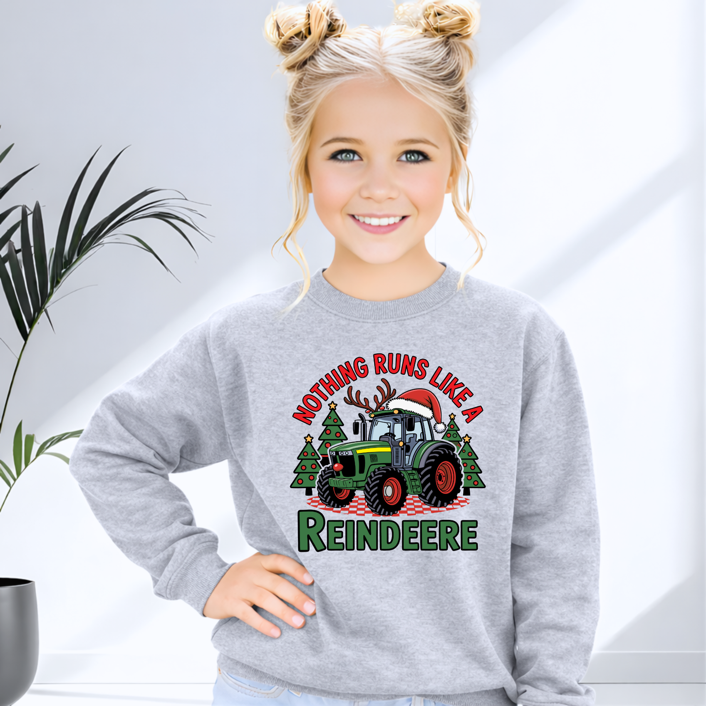 Child wearing a gray sweatshirt with a Christmas-themed design featuring a tractor and reindeer.
