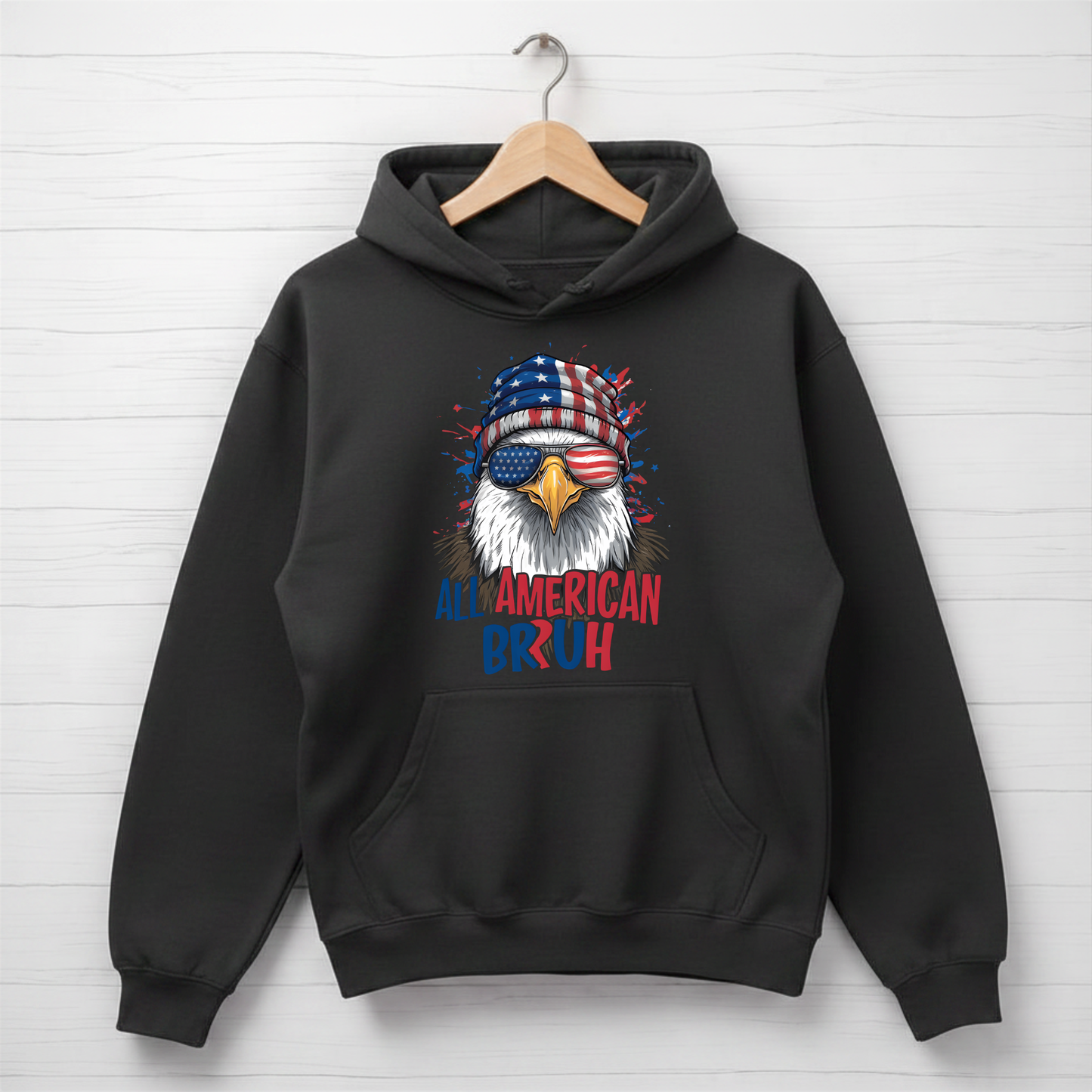 Black hoodie with an eagle design and 'All American Bruh' text on a white wooden background