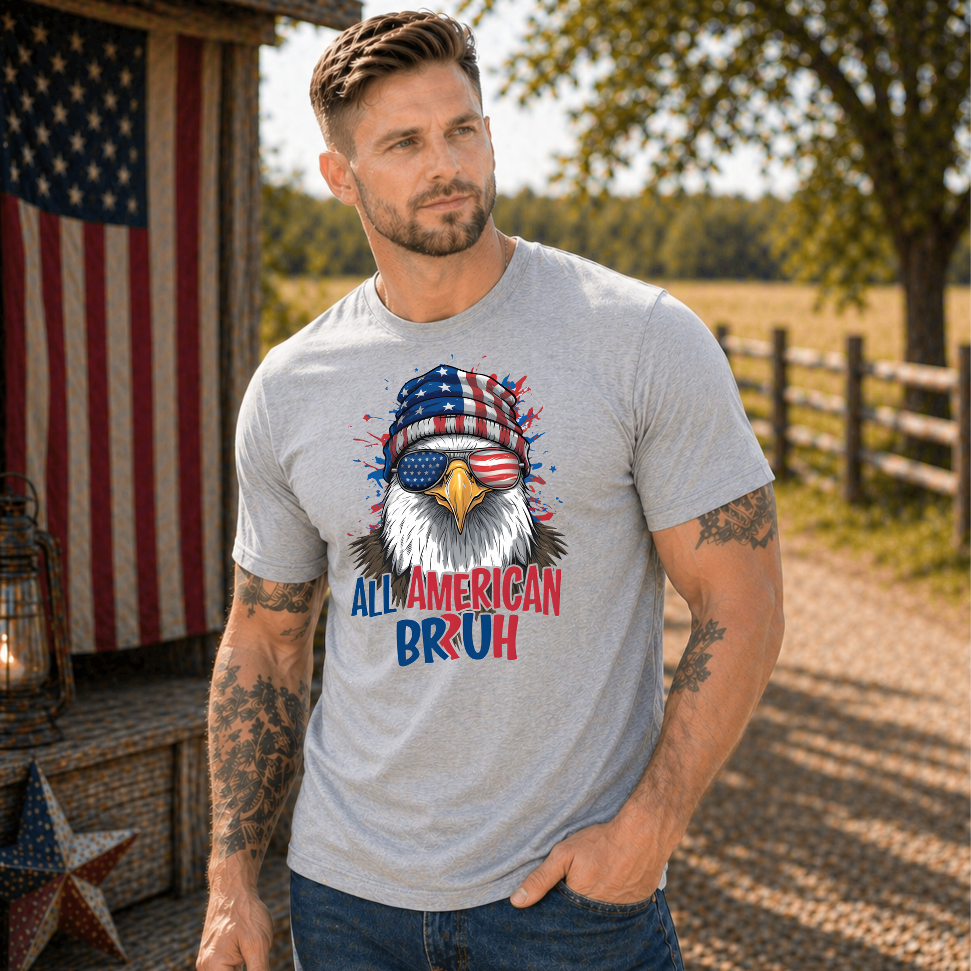 Man wearing a t-shirt with an eagle graphic and text, standing outdoors with American flag and barn in background.