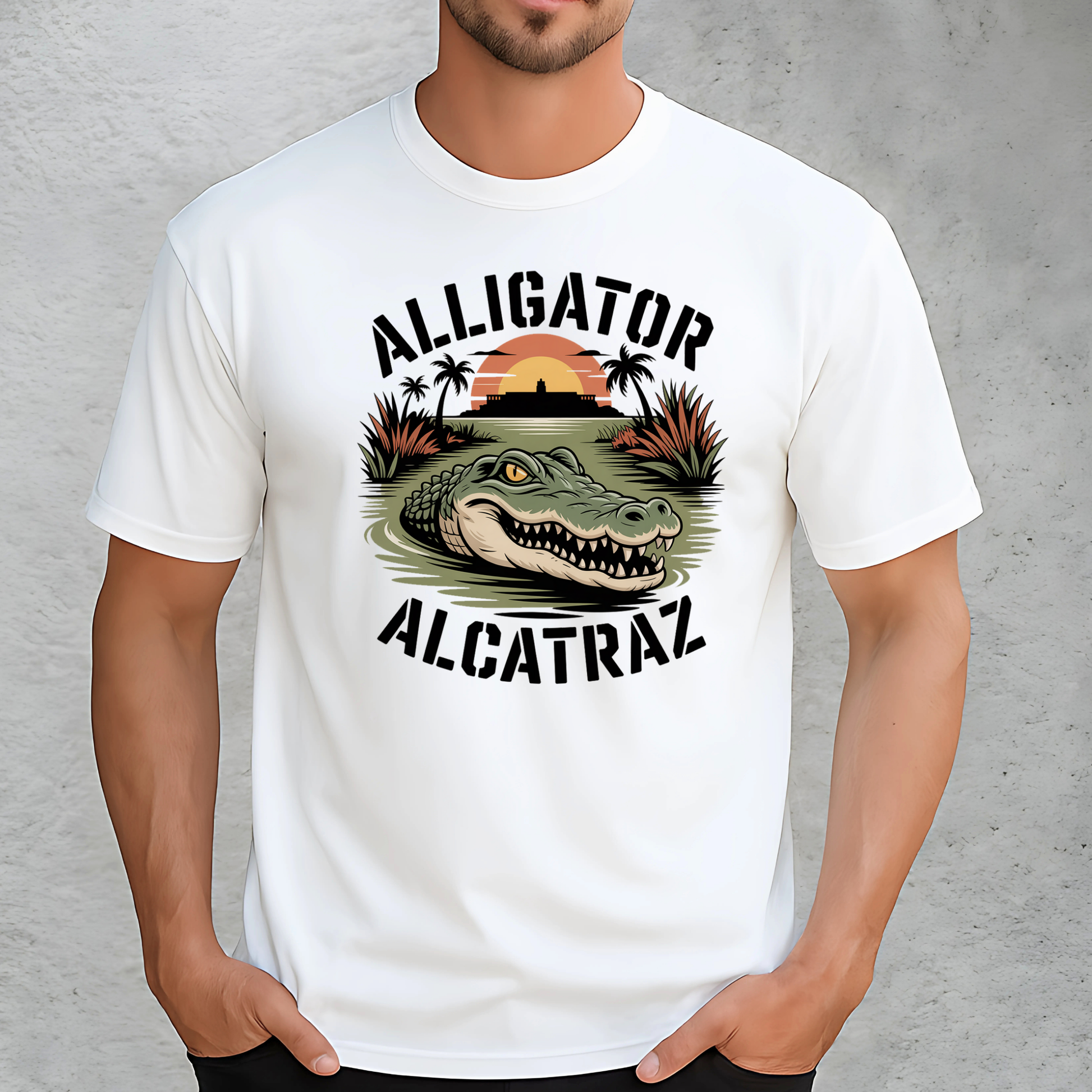 Close-up of a man in a white Alligator Alcatraz shirt with bold swamp and gator print. Features the historic Alcatraz island backdrop and sunset scene. Unisex fit ideal for casual wear, gifts, or tourist apparel.