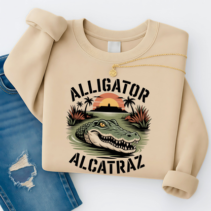 Women’s beige Alligator Alcatraz sweatshirt, soft fleece graphic pullover featuring alligator and Alcatraz Island design, styled with distressed jeans and gold necklace"