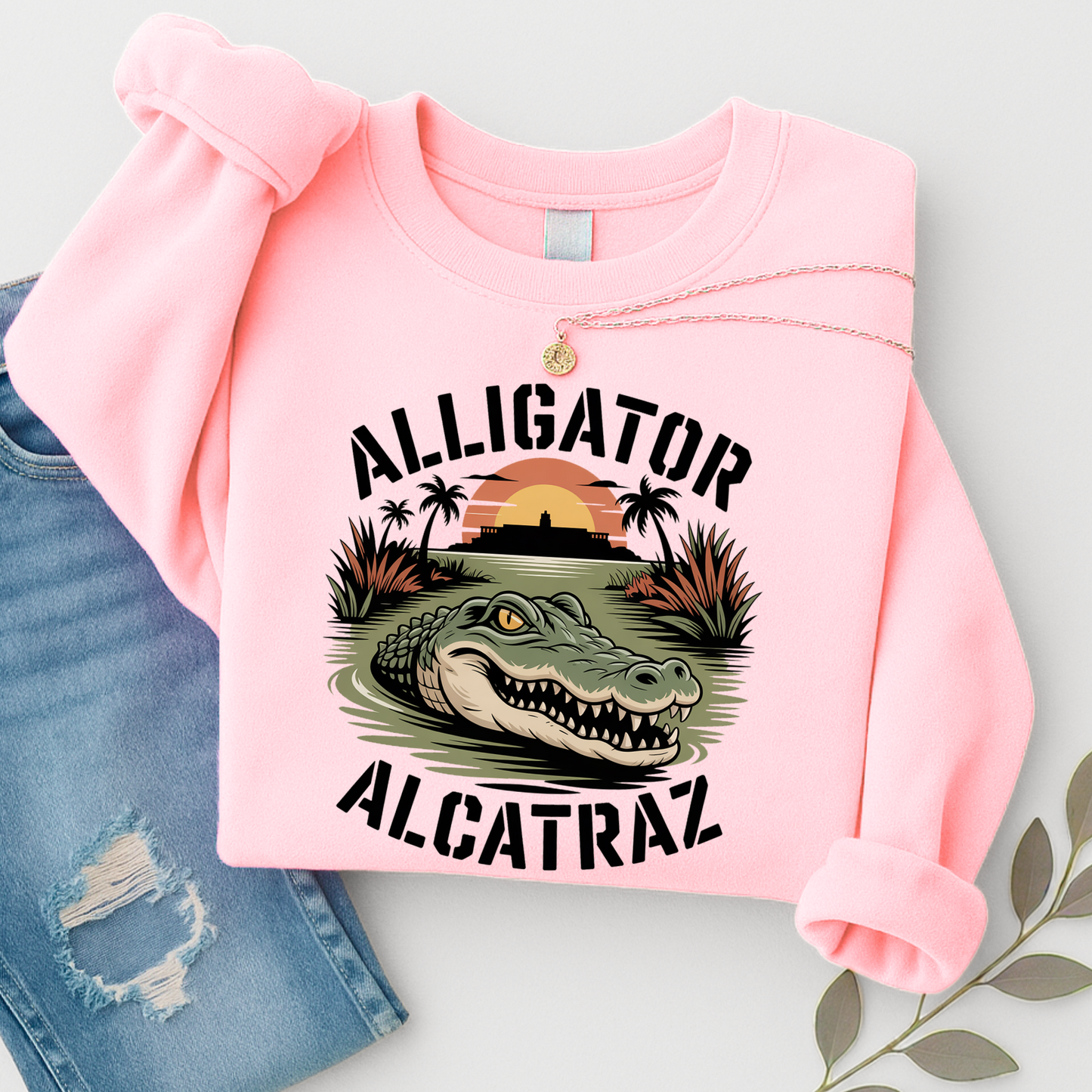 Pink sweatshirt with alligator graphic and text on a light gray background
