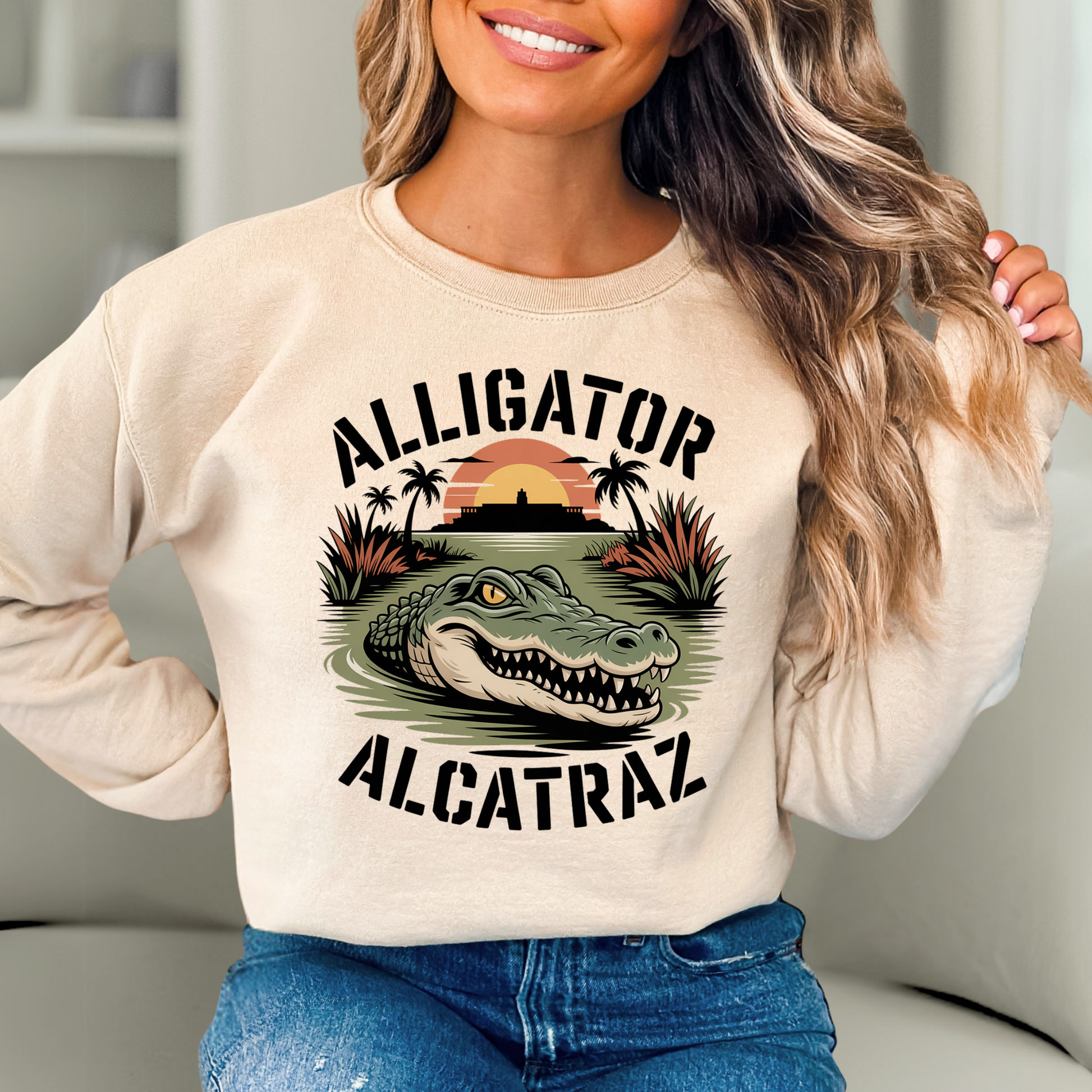 Woman wearing sand colored Alligator Alcatraz sweatshirt with bold alligator and sunset island graphic, cozy women’s casual pullover for travel or lounging