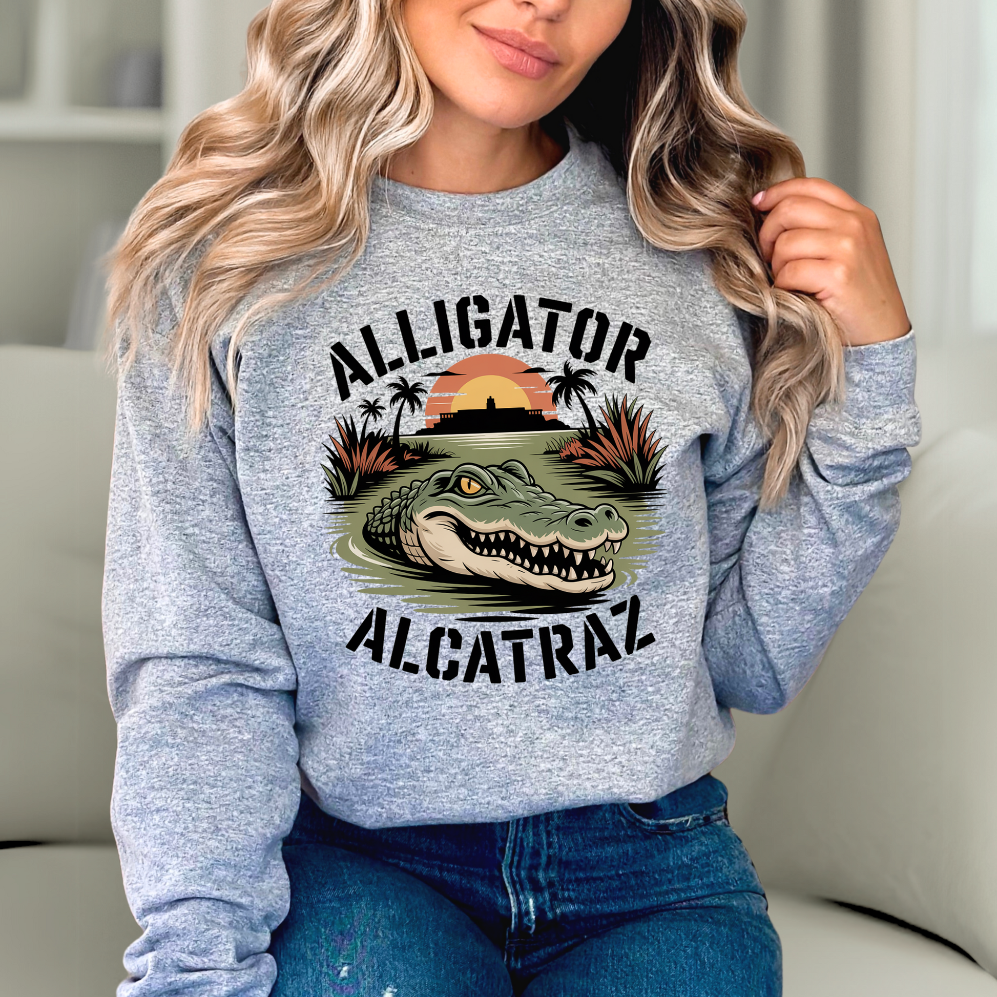 Woman wearing gray Alligator Alcatraz sweatshirt with bold alligator and sunset island graphic, cozy women’s casual pullover for travel or lounging