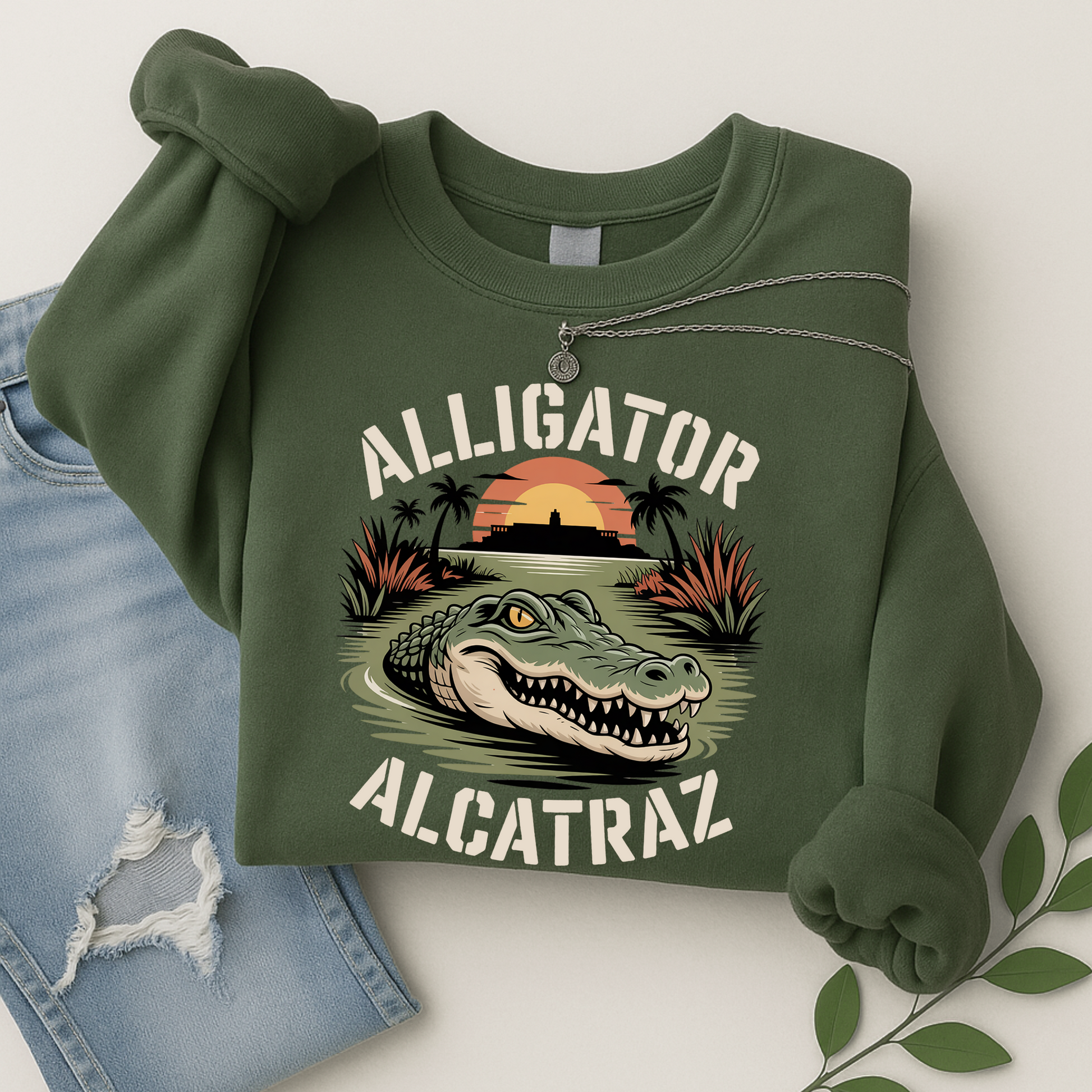 Women’s olive green Alligator Alcatraz sweatshirt, soft fleece pullover with alligator and Alcatraz Island print, styled with ripped jeans and silver necklace