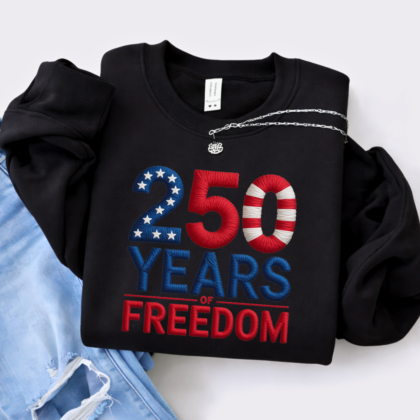 Black sweatshirt with 250 Years of Freedom patriotic design folded with jeans