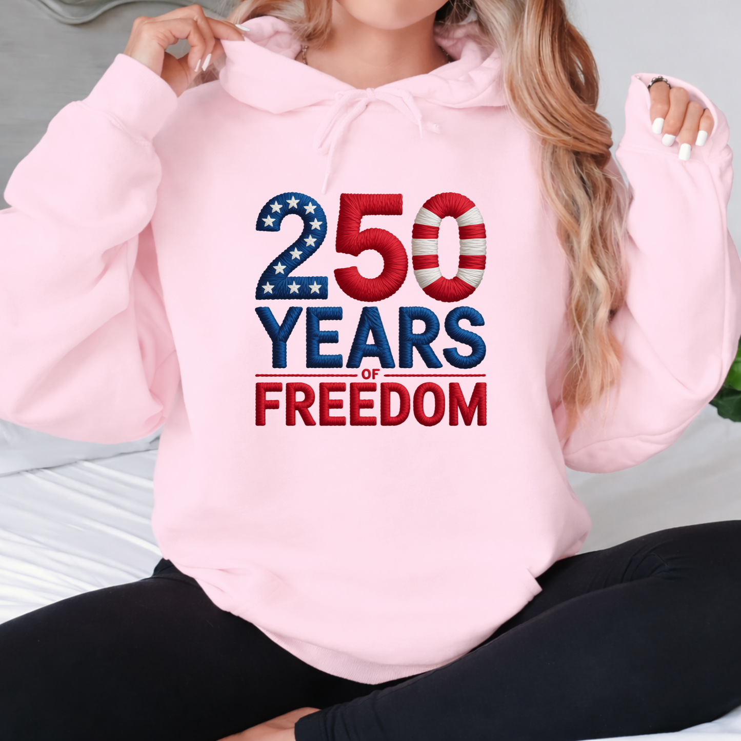 Pink hoodie with 250 Years of Freedom patriotic design worn with hood held up