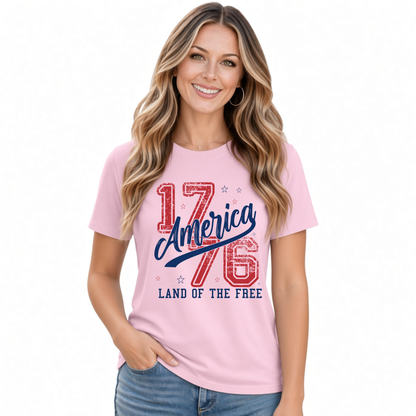 Smiling woman wearing a light pink T-shirt with a distressed red and blue America 1776 Land of the Free graphic
