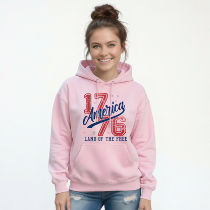 Woman wearing a light pink pullover hoodie with a distressed red and blue America 1776 Land of the Free graphic