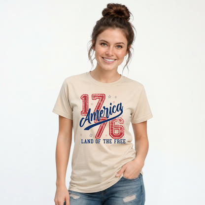 Woman wearing a sand T-shirt with a distressed red and blue America 1776 Land of the Free graphic
