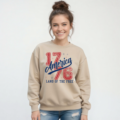 Woman wearing a sand crewneck sweatshirt with a distressed red and blue America 1776 Land of the Free graphic