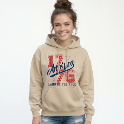 Woman wearing a sand pullover hoodie with a distressed red and blue America 1776 Land of the Free graphic