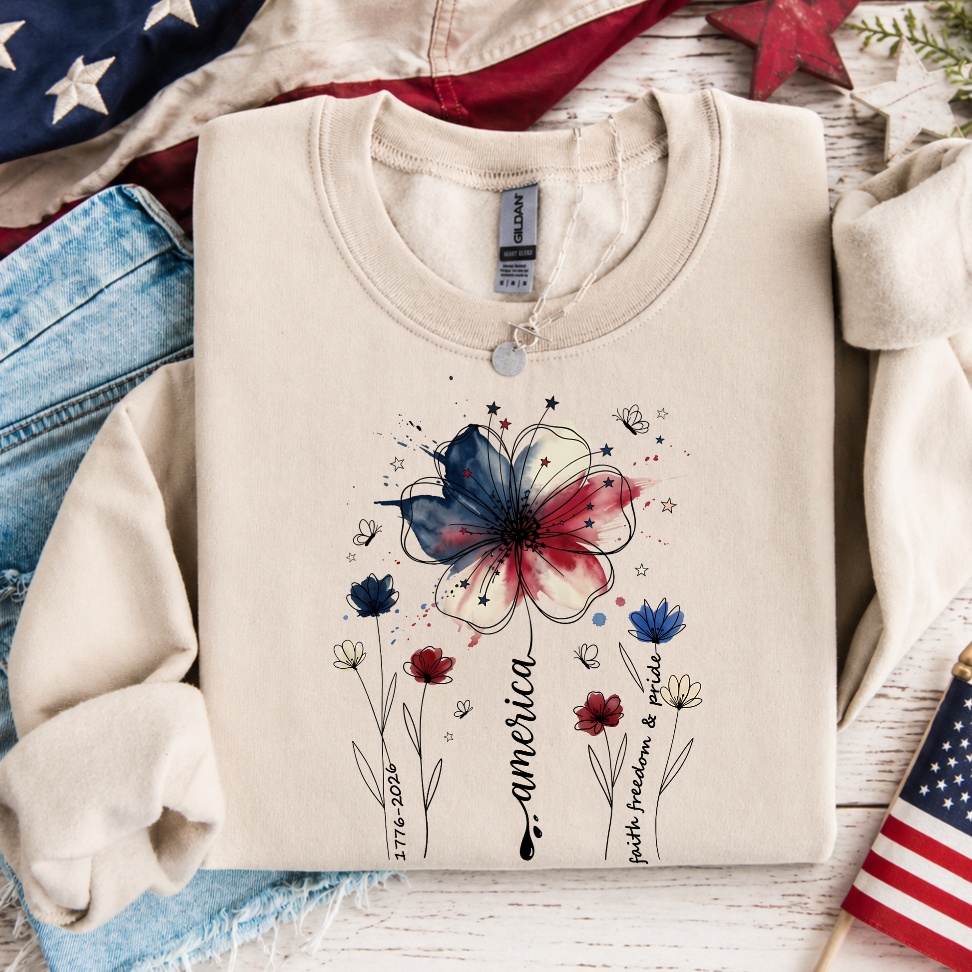 Sand colored patriotic floral sweatshirt featuring America 250 watercolor flower design and Faith Family Freedom artwork
