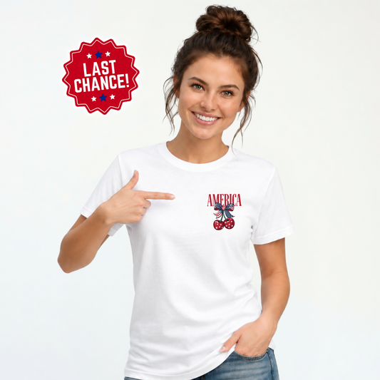 A woman wearing a white graphic t-shirt with a patriotic 'AMERICA' and cherries design on the left chest, pointing to the graphic. A red 'LAST CHANCE!' badge is in the top left corner.