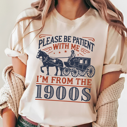 Woman in sand T-shirt with vintage horse carriage graphic and Please Be Patient With Me I’m From the 1900s text – casual retro unisex tee gift idea