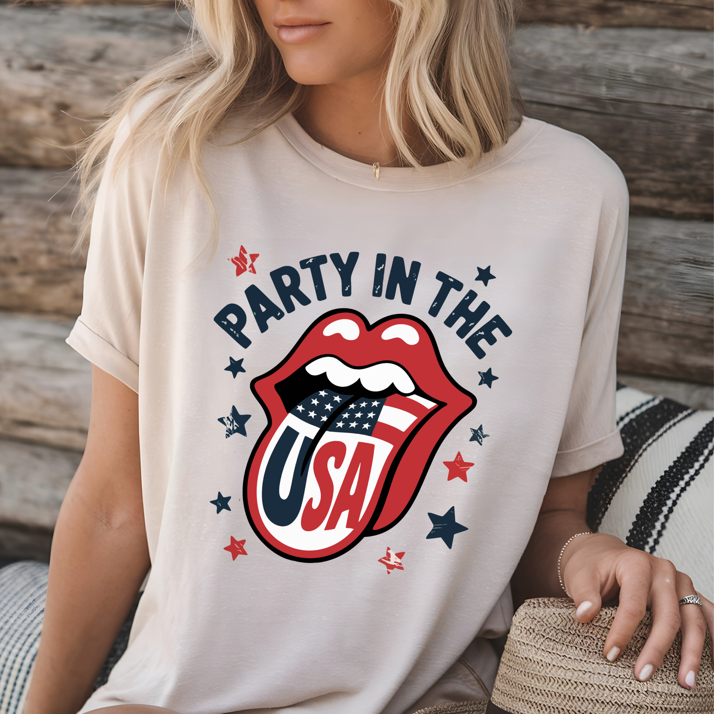 Blonde woman seated in a sand-colored “Party in the USA” graphic tee with red lips and American flag tongue. Casual and comfy look for Independence Day, USA events, or country-themed summer style.

