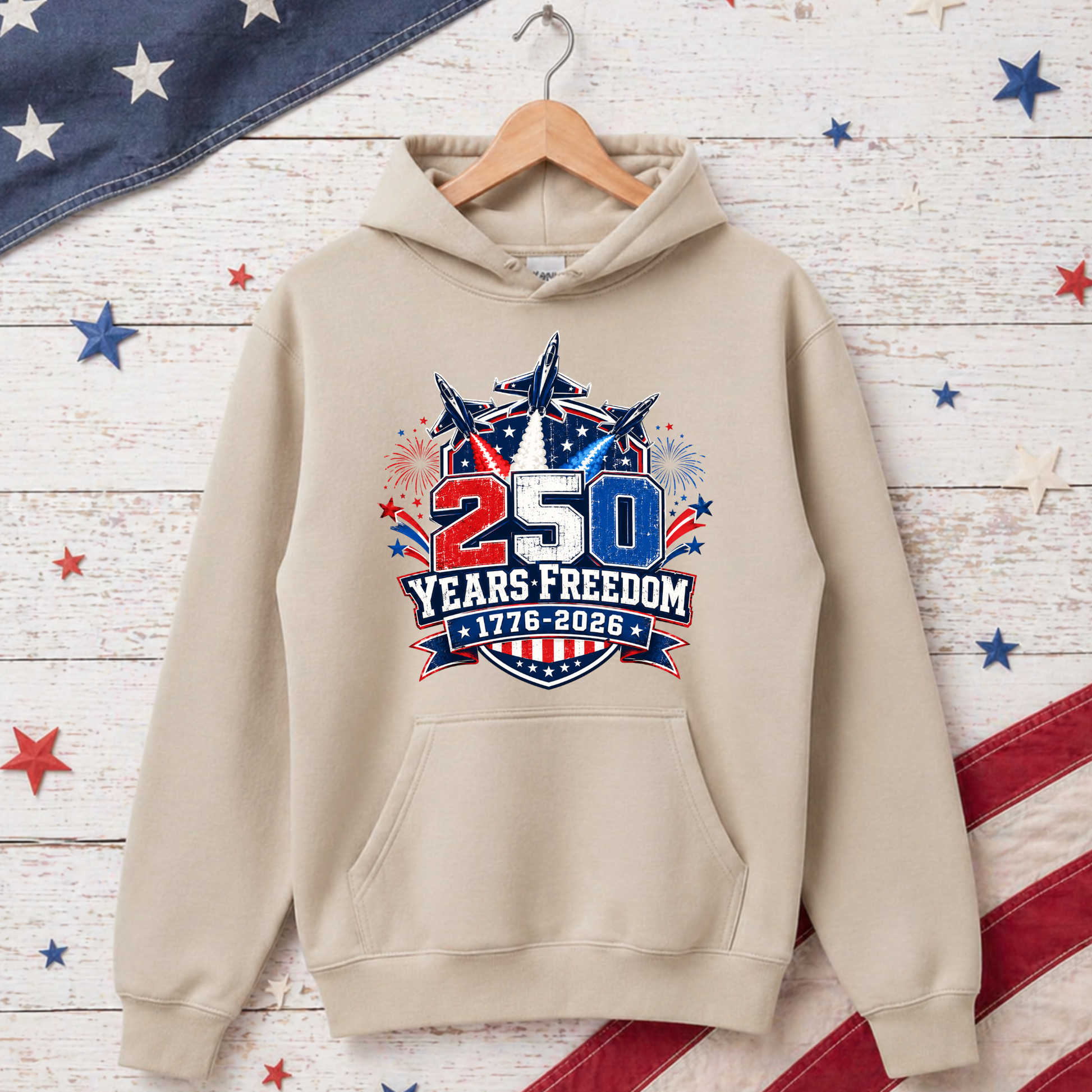 Beige hoodie with '250 Years Freedom' design on a wooden background with American flag decorations.