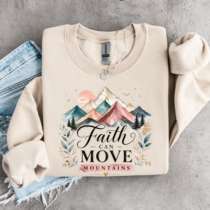 Beige sweatshirt with mountain design and 'Faith Can Move Mountains' text on a gray surface.