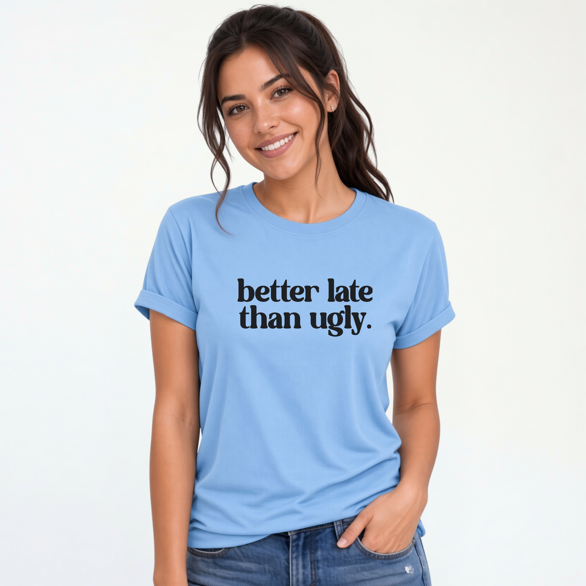 Woman wearing a light blue short-sleeve T-shirt with black Better Late Than Ugly lettering against a white studio background.