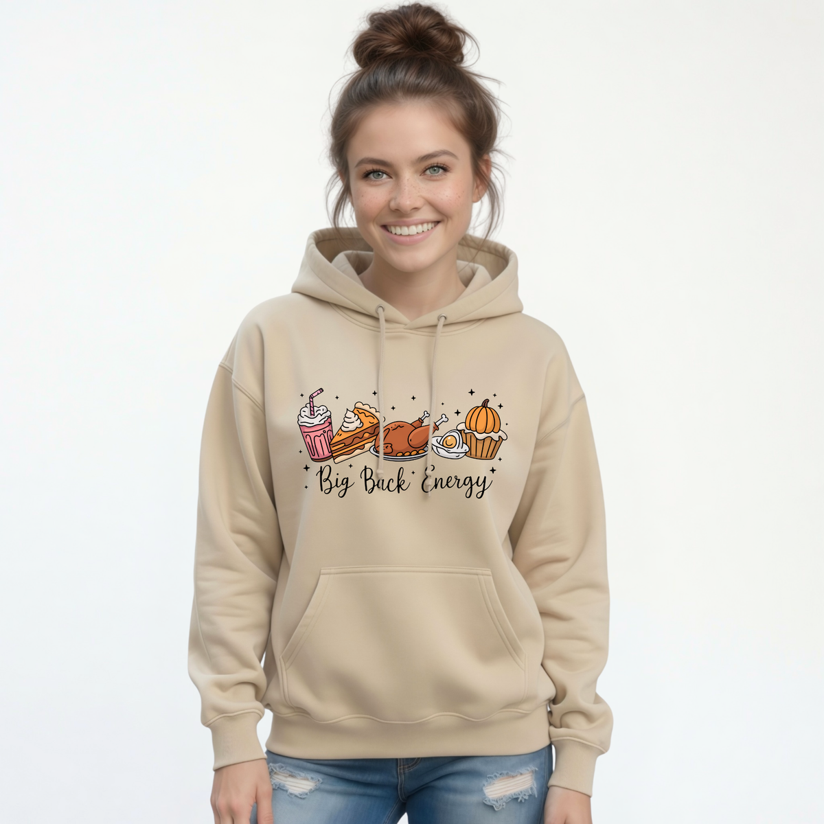 Sand pullover hoodie with a Big Back Energy Thanksgiving food graphic shown on a woman in jeans against a plain white backdrop.