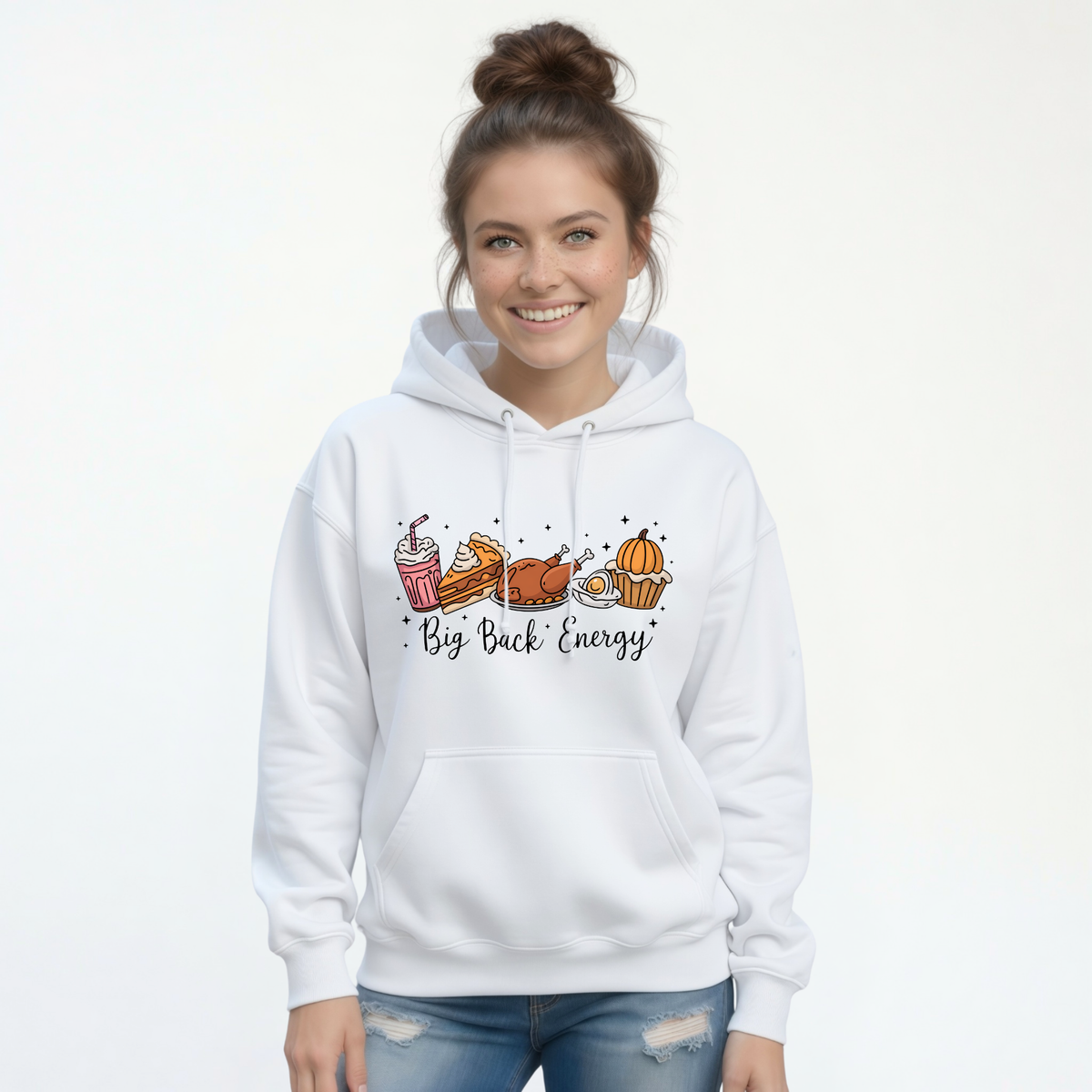 White pullover hoodie displays the Big Back Energy fall food design with pumpkin and pie, styled with blue jeans.