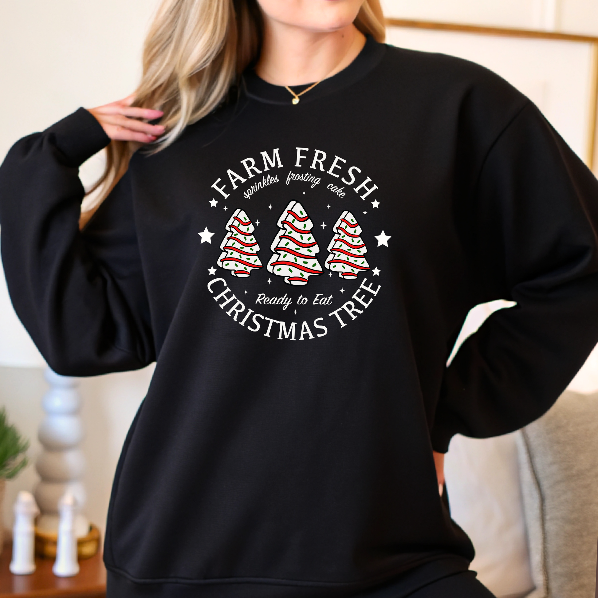 Black sweatshirt with Christmas tree design and text worn by a person indoors.