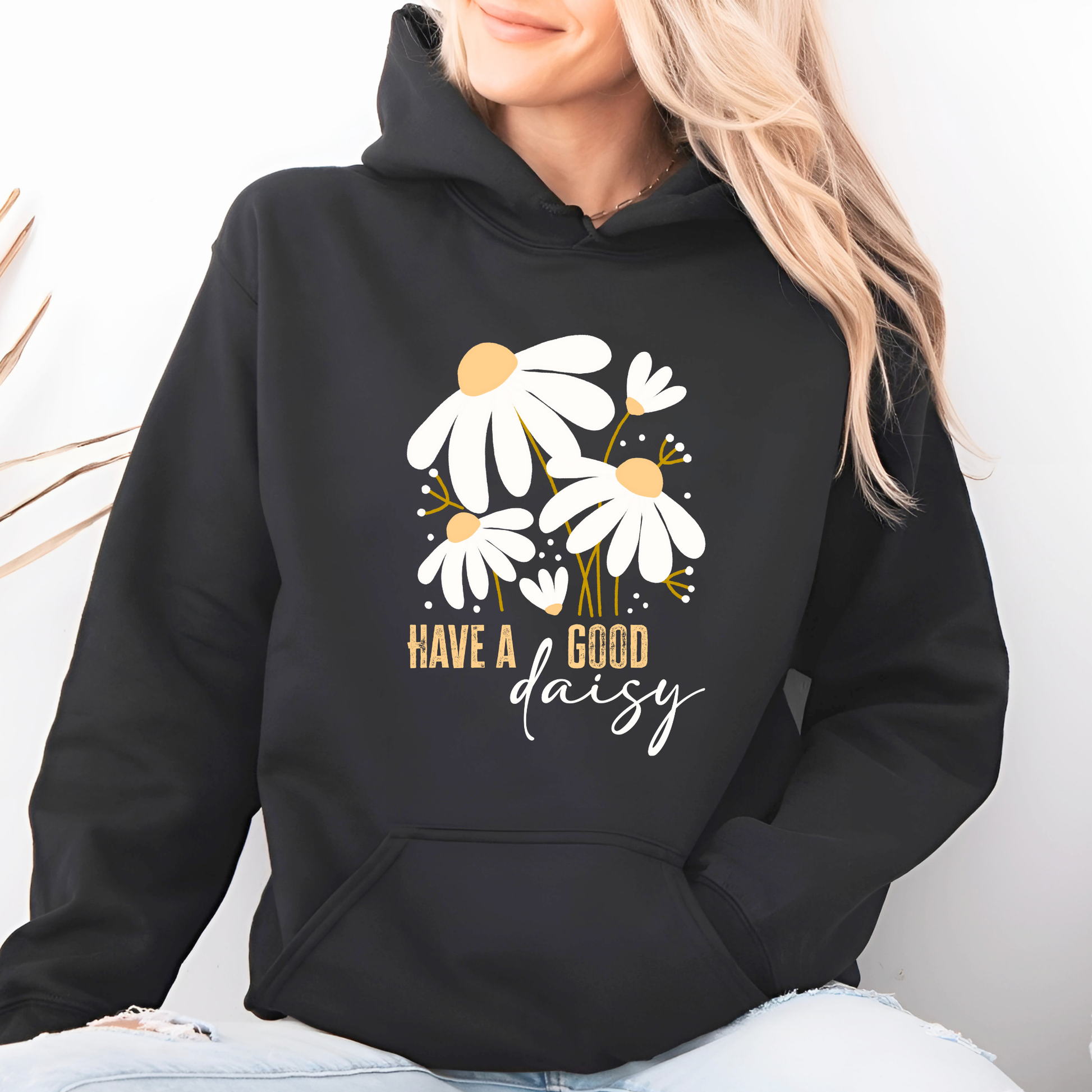 Black hoodie with floral design and text 'Have a good daisy' worn by a woman.
