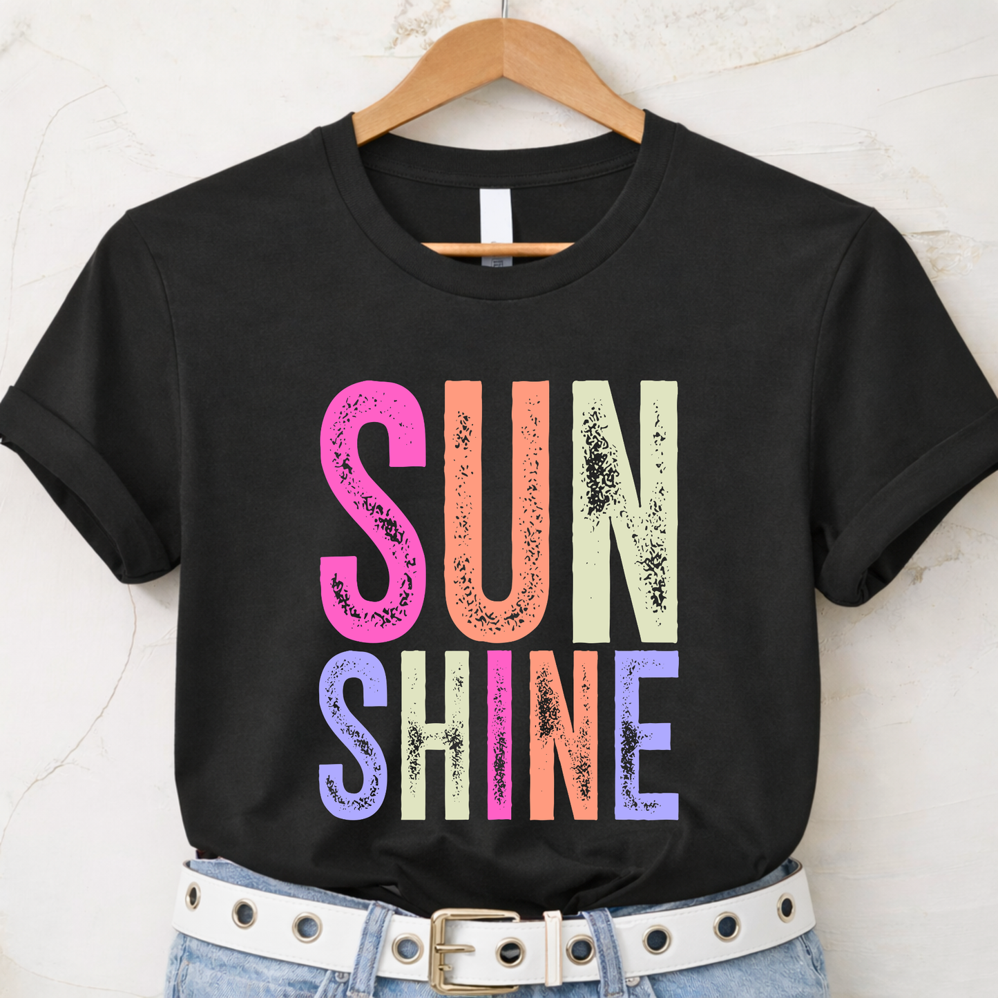 Black t-shirt with 'SUNSHINE' in colorful letters on a hanger.