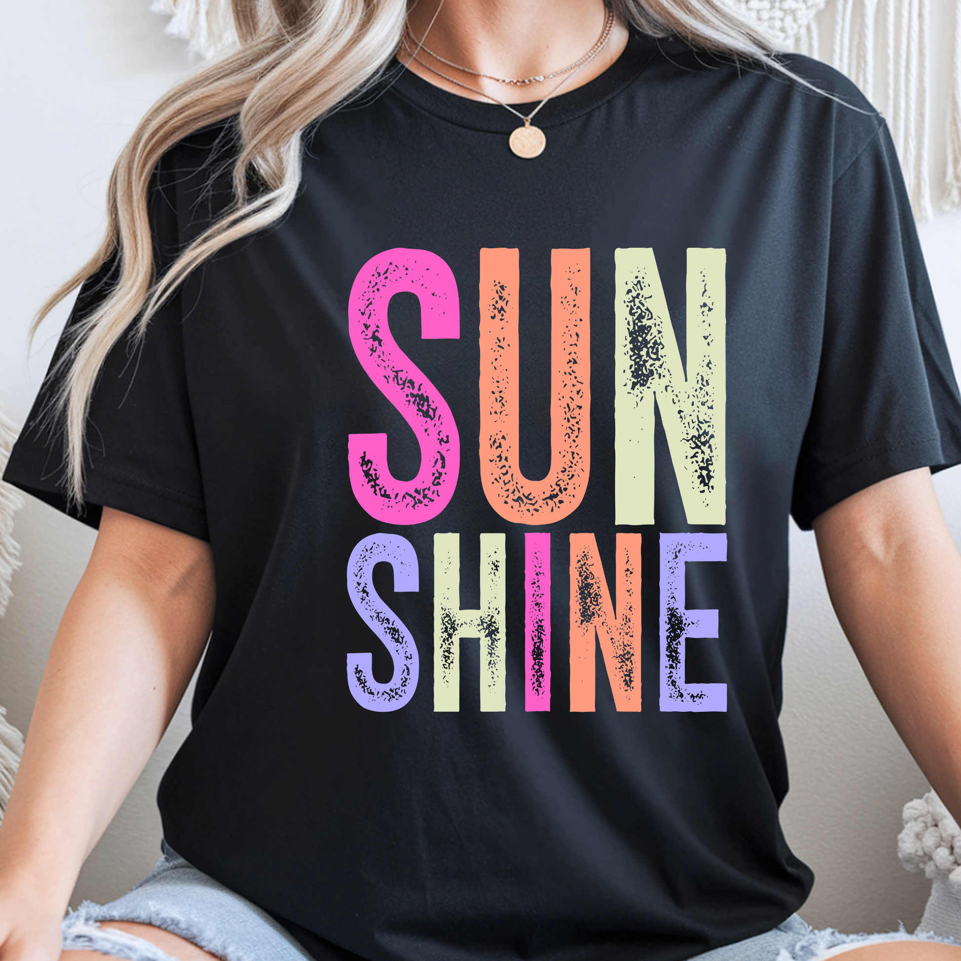 Black t-shirt with colorful 'SUNSHINE' text worn by a person.