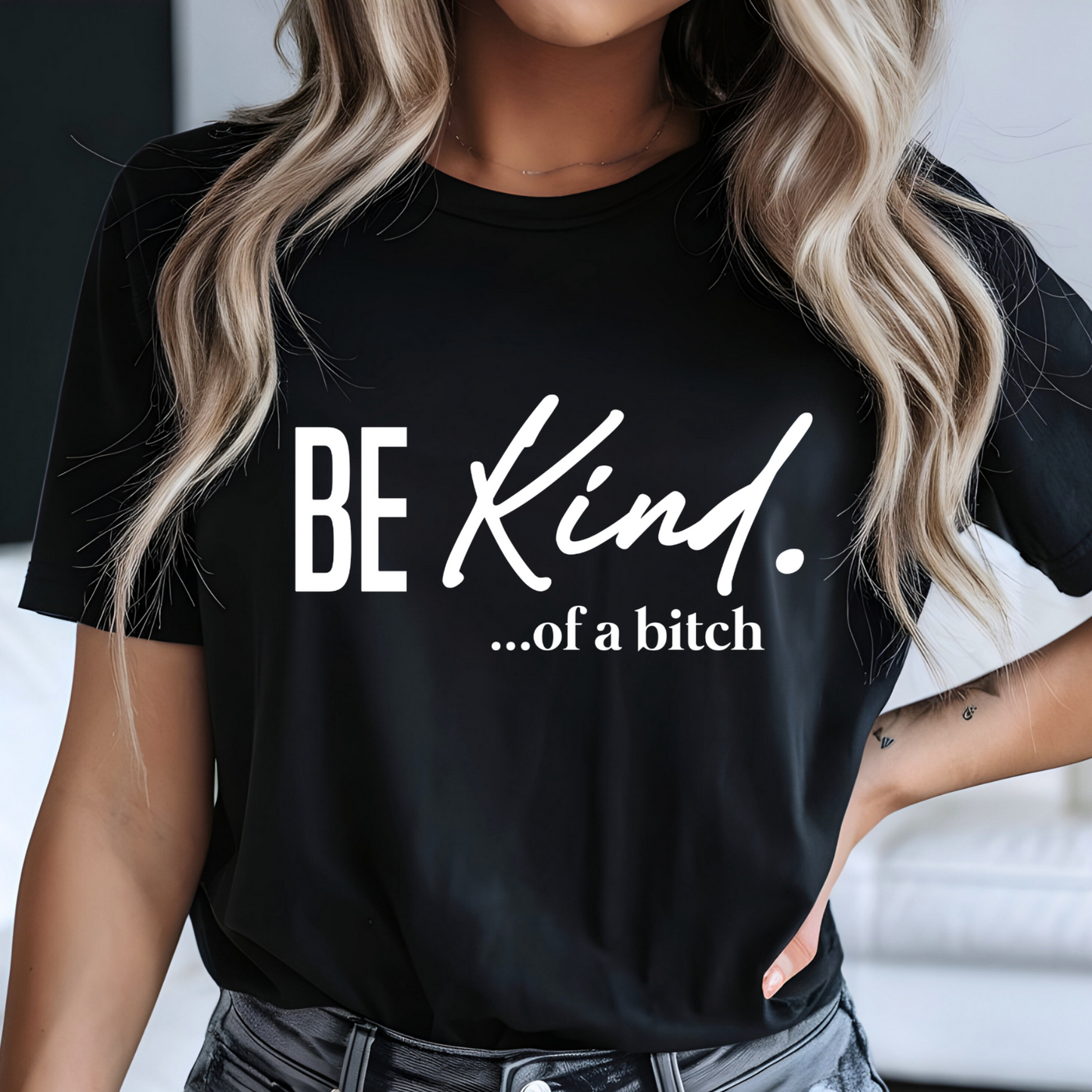Black shirt with white script text reading “Be Kind…of a bitch” on woman in edgy outfit

