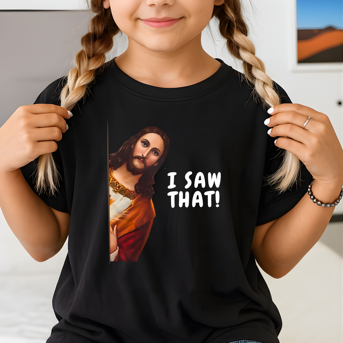 Child wearing a black t-shirt with a graphic of Jesus saying 'I SAW THAT!' text.